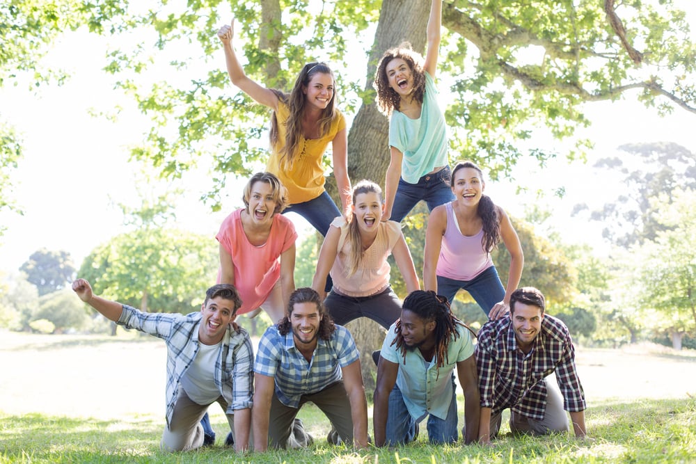 Happy friends in the park making human pyramid on a sunny day